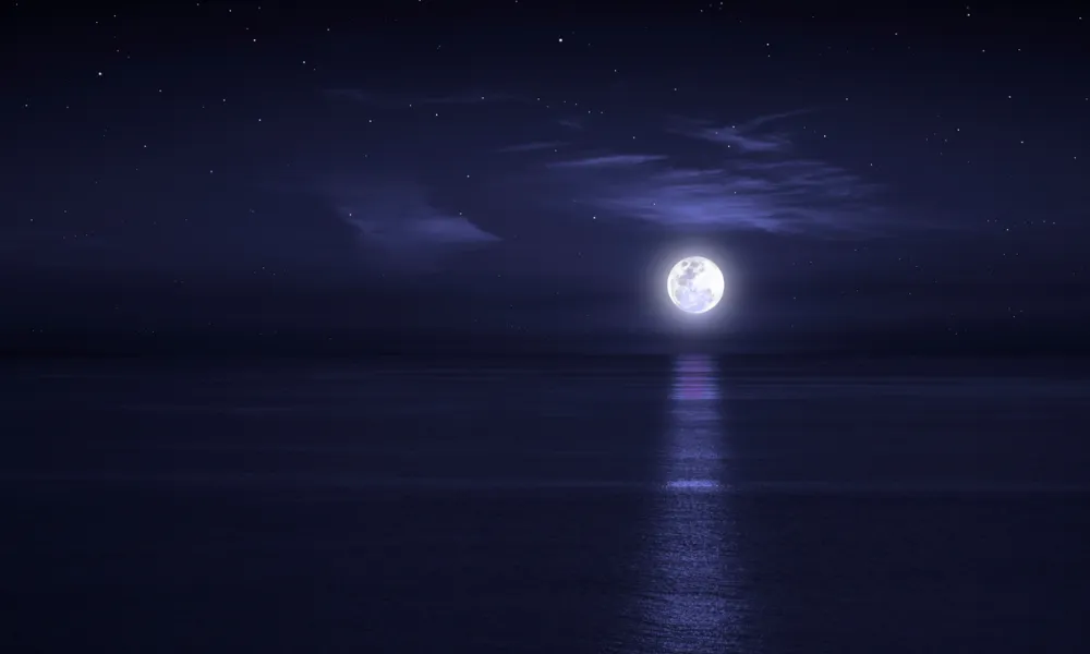 full moon over the ocean with dark night sky 